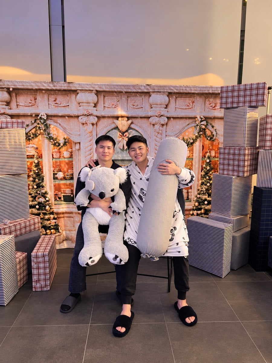 Co-founders Trevor (left, holding a koala plush) and Farrell (right, holding a Koalu body pillow) sitting side by side